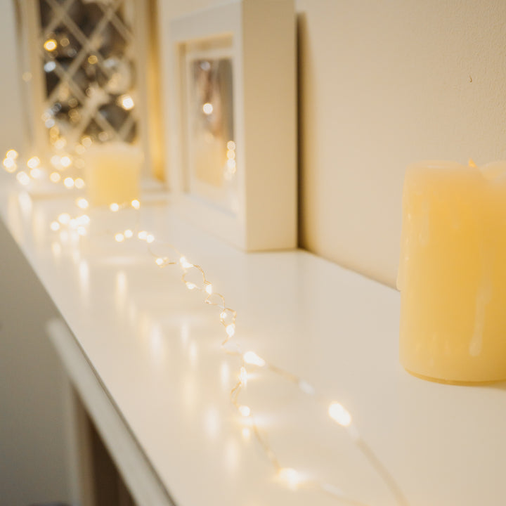 White mantle adorned with 100 LED Micro Lights, candles, and a picture