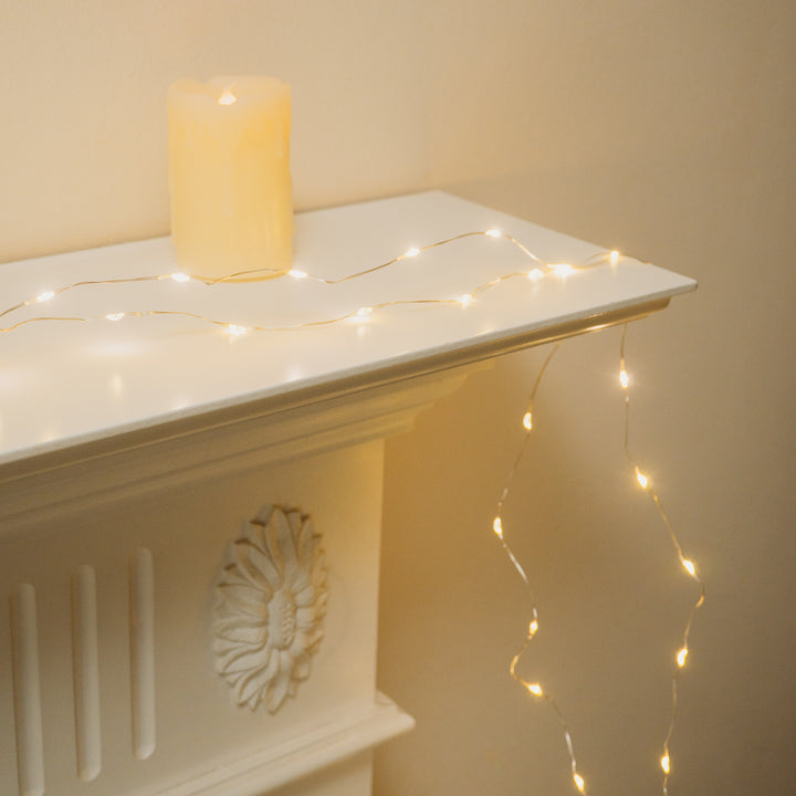 White mantle decorated with 100 LED Micro Lights and a candle