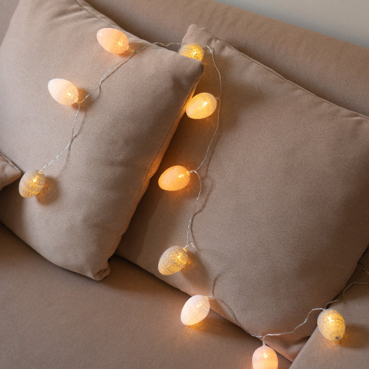 A couch setup featuring pillows and 10 LED Cotton Egg Lights