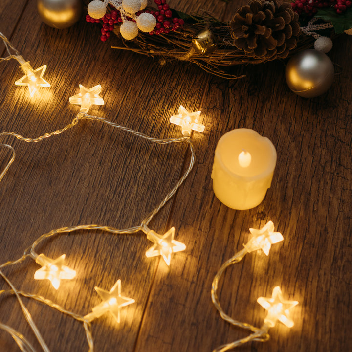 Star LED lights alongside a candle on a wooden table
