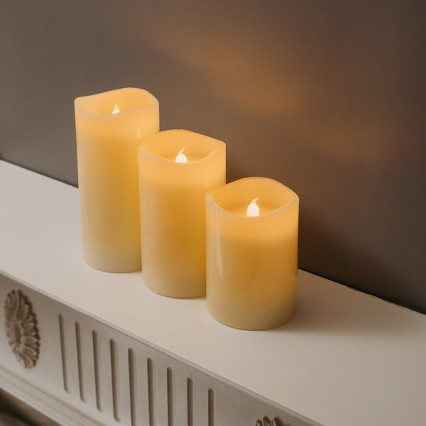 Three-piece LED candle set arranged on a shelf near a fireplace