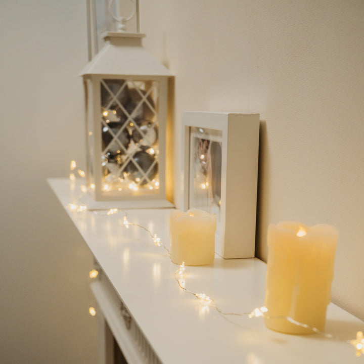 White shelf decorated with 40 LED Star Timer Lights, candles, and a lantern