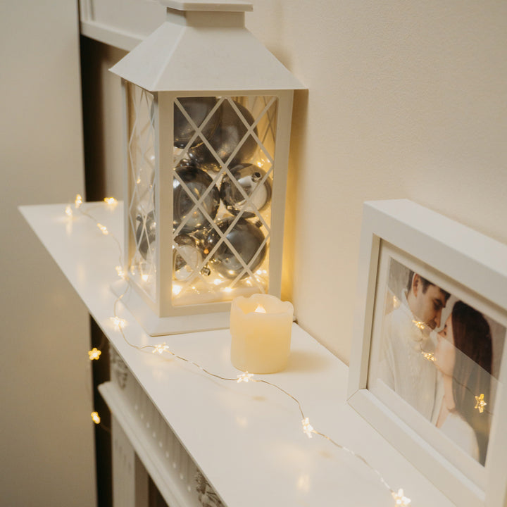 White shelf adorned with a candle, a picture, and the 40 LED Star Timer Lights